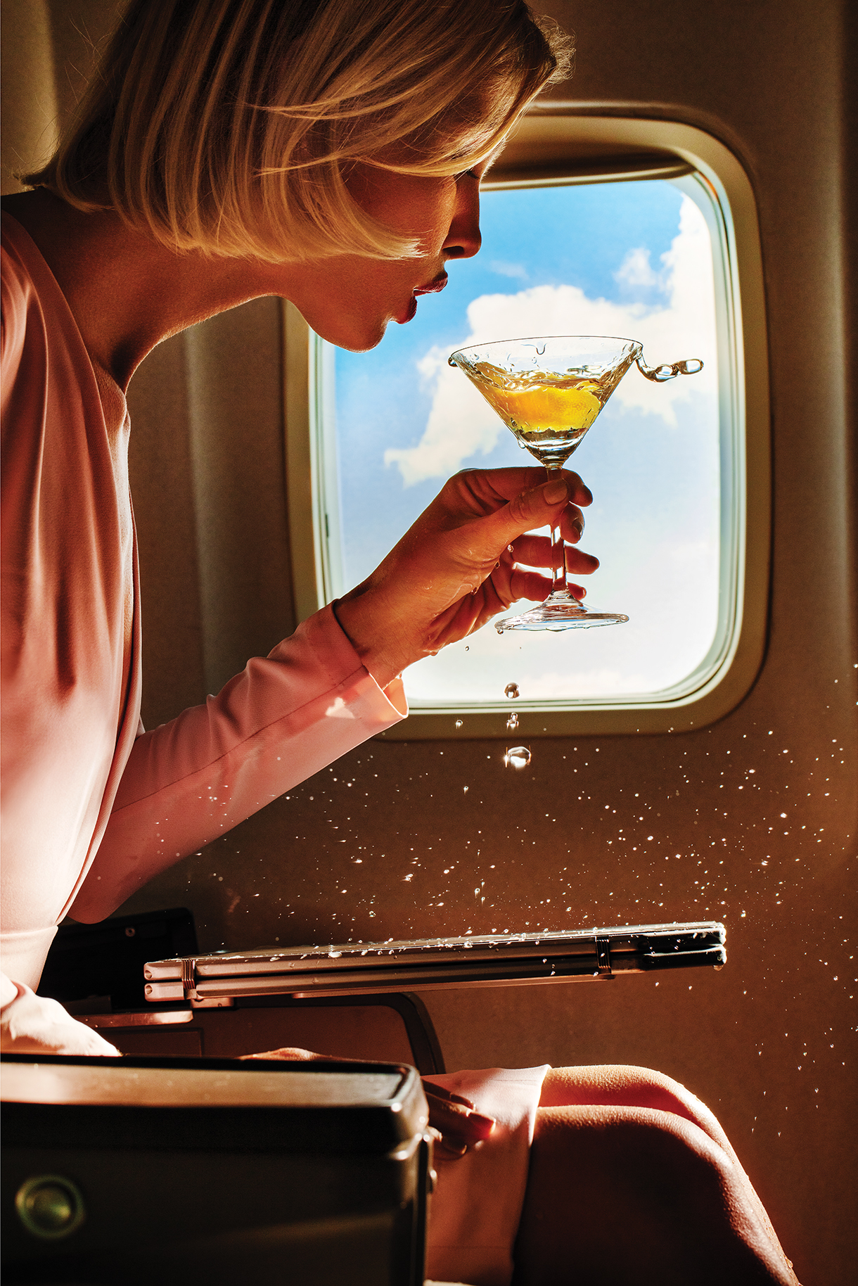 Woman drinking a martini on an airplane during turbulence